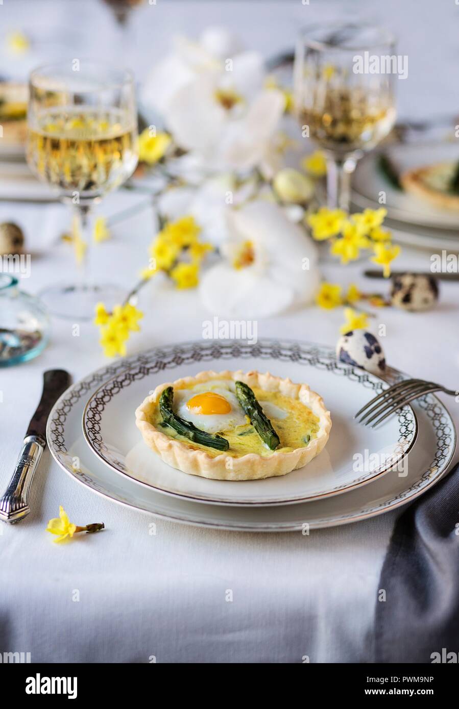 Asparagus quiche with fried quail egg on a dining table set for Easter