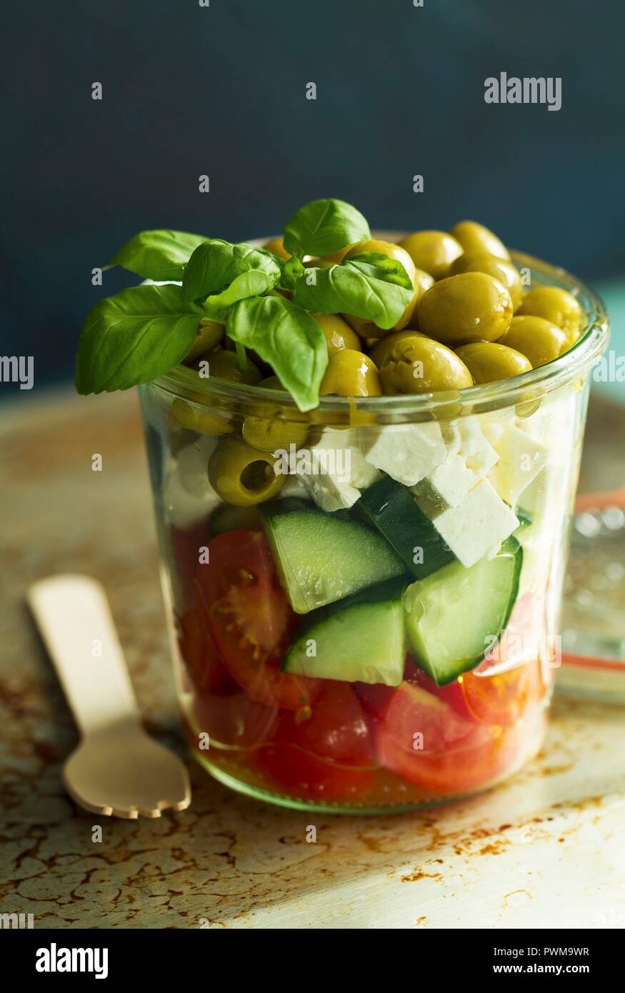A salad of tomatoes, cucumbers, feta, green olives and basil in a glass Stock Photo
