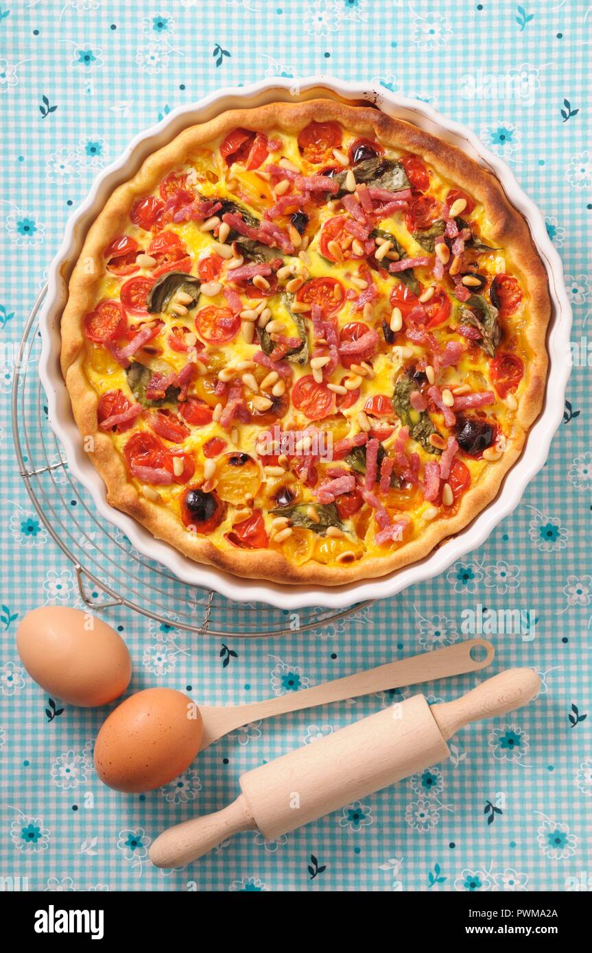 Quiche with cherry tomatoes, spinach, bacon and pine nuts Stock Photo