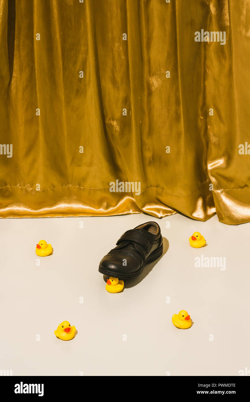 A black shoe squashed a rubber duck Stock Photo