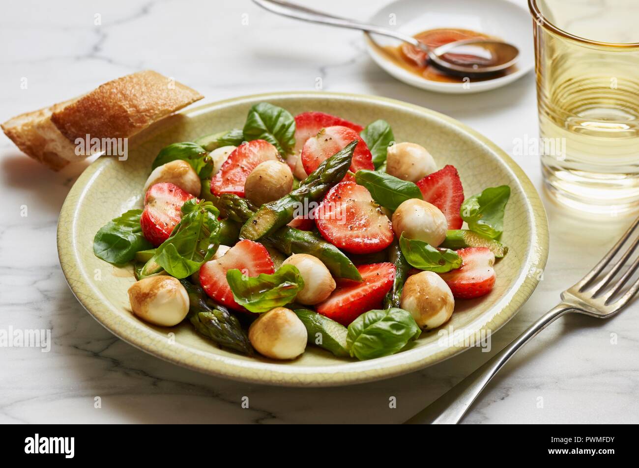 A salad with green asparagus, strawberries, mini mozzarella balls and fresh basil Stock Photo