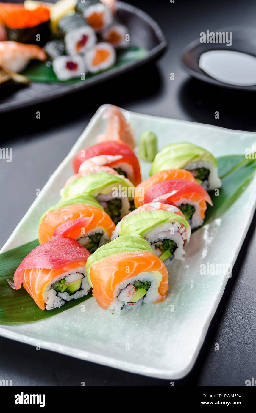 Japanese platter of rainbow rolls maki, inside out seaweed and rice roll filled with cucumber, mayonnaise, avocado, crub stick topped with fresh salmo Stock Photo