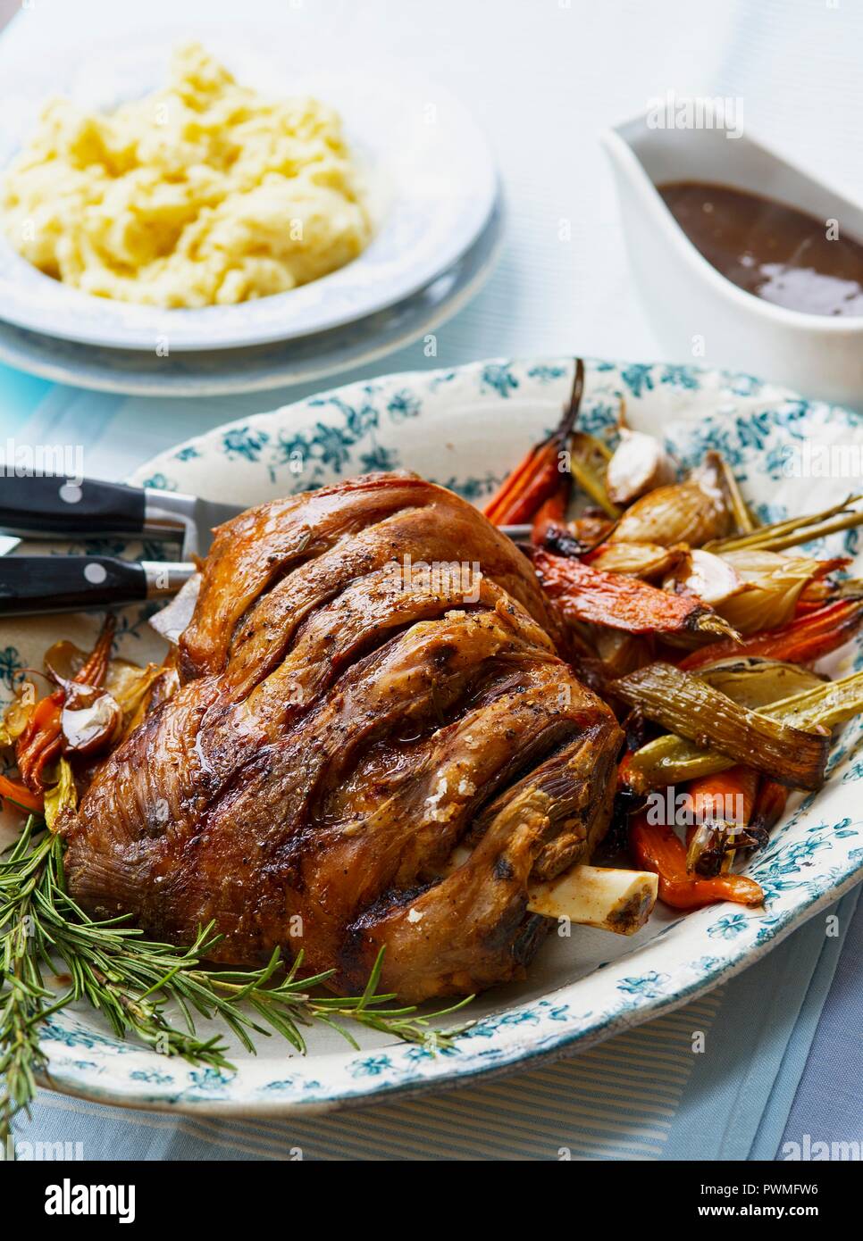 Roast shoulder of lamb with vegetables, rosemary, mashed potatoes and gravy Stock Photo