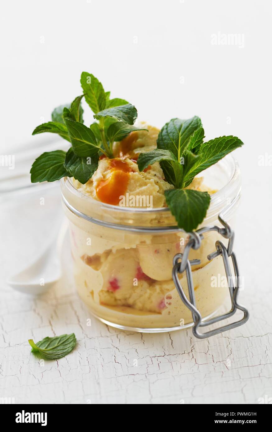 Vanilla and strawberry ice cream with fruit sauce and mint in a mason jar Stock Photo