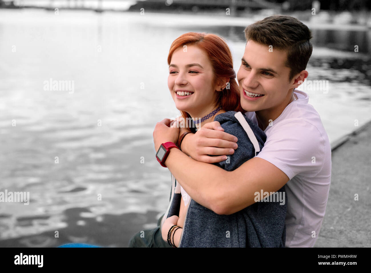 Loving beaming handsome boyfriend hugging his good-looking girlfriend Stock Photo