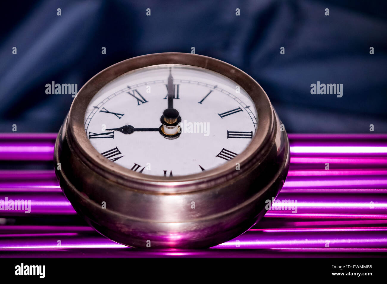 Arty shot of a metal large pocket watch clock on purple pipes Stock Photo