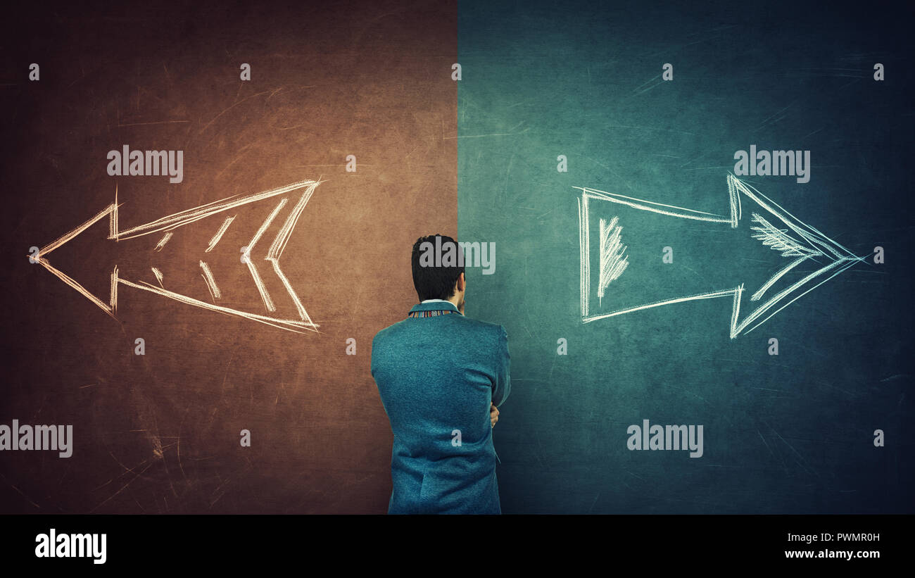 Puzzled businessman and a split blackboard with arrows going in two different ways red and blue side. Correct choice between left and right, failure o Stock Photo