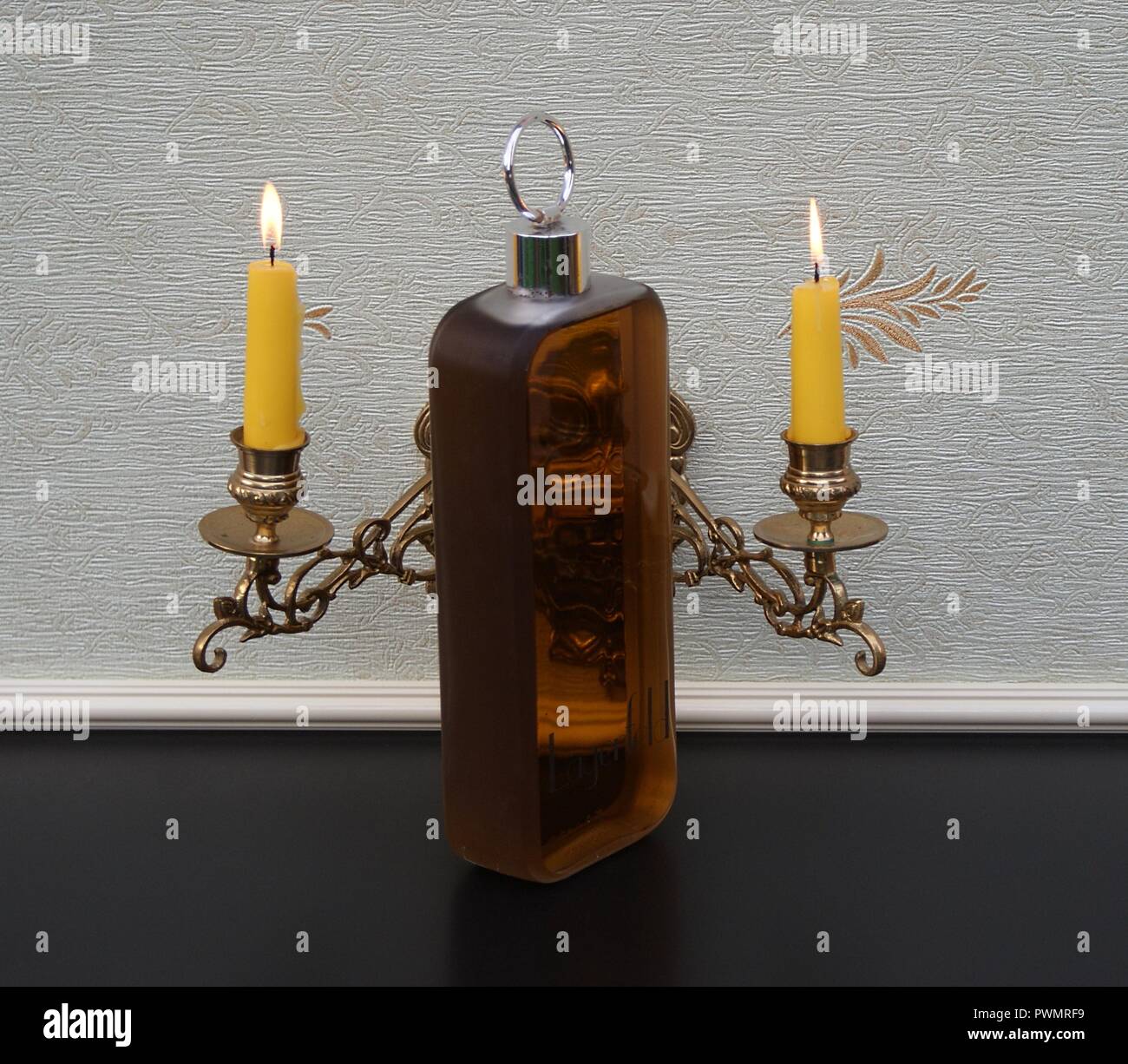 Lagerfeld, men's fragrance, large perfume bottle in front of a piano candelabra with shining candles Stock Photo