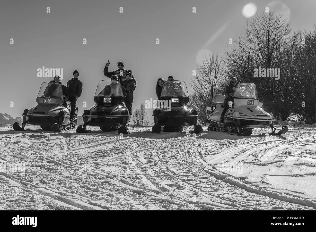 Adygea, Russia - January 23,  2017: Young happy men, women and children on the snowmobiles Yamaha on a snowy slope winter Sunny day, black and white p Stock Photo