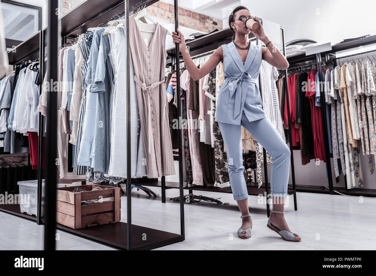 Woman Shopping In Boutique Drinking Coffee Before Going To