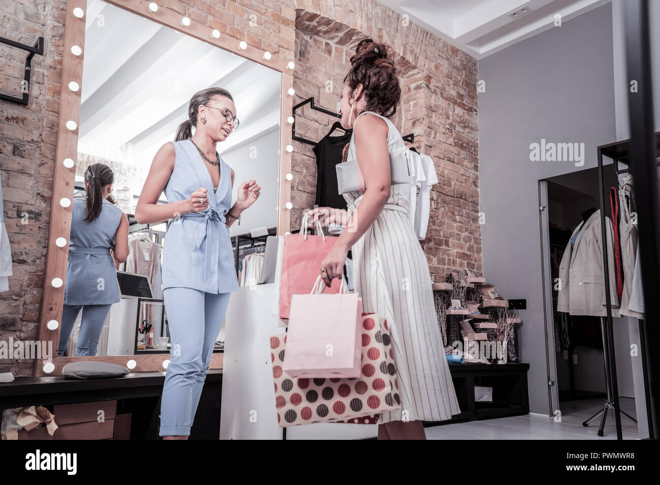 Woman wearing striped dress leaving showroom with many purchases Stock Photo