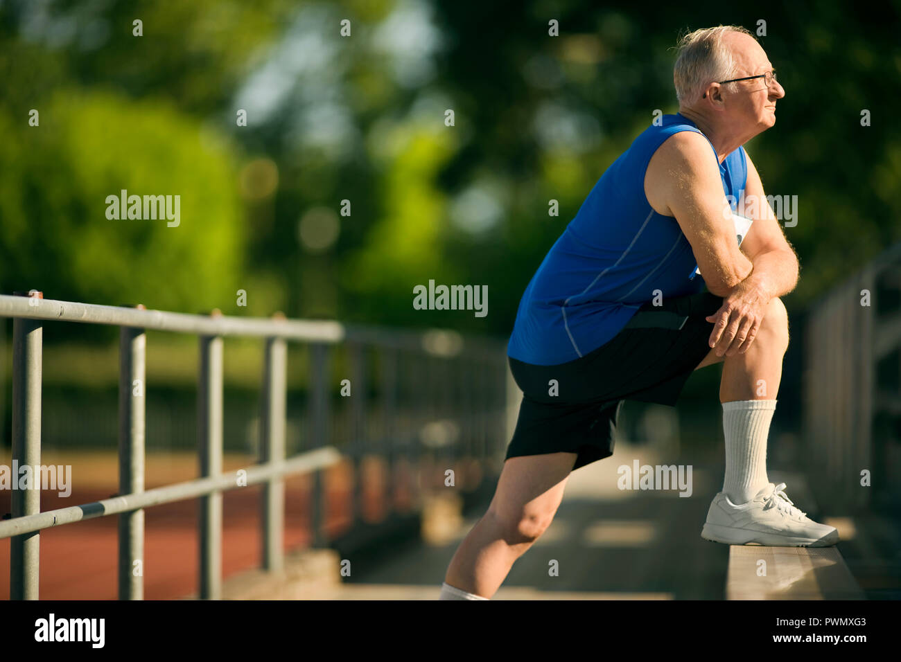 Senior man warming up with stretches on bleachers. Stock Photo