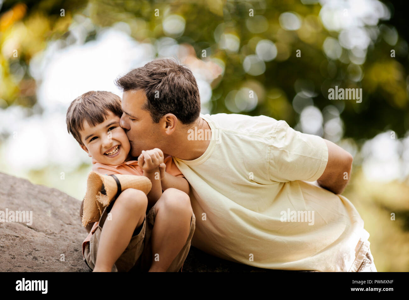 Father kissing his smiling young son on the cheek. Stock Photo