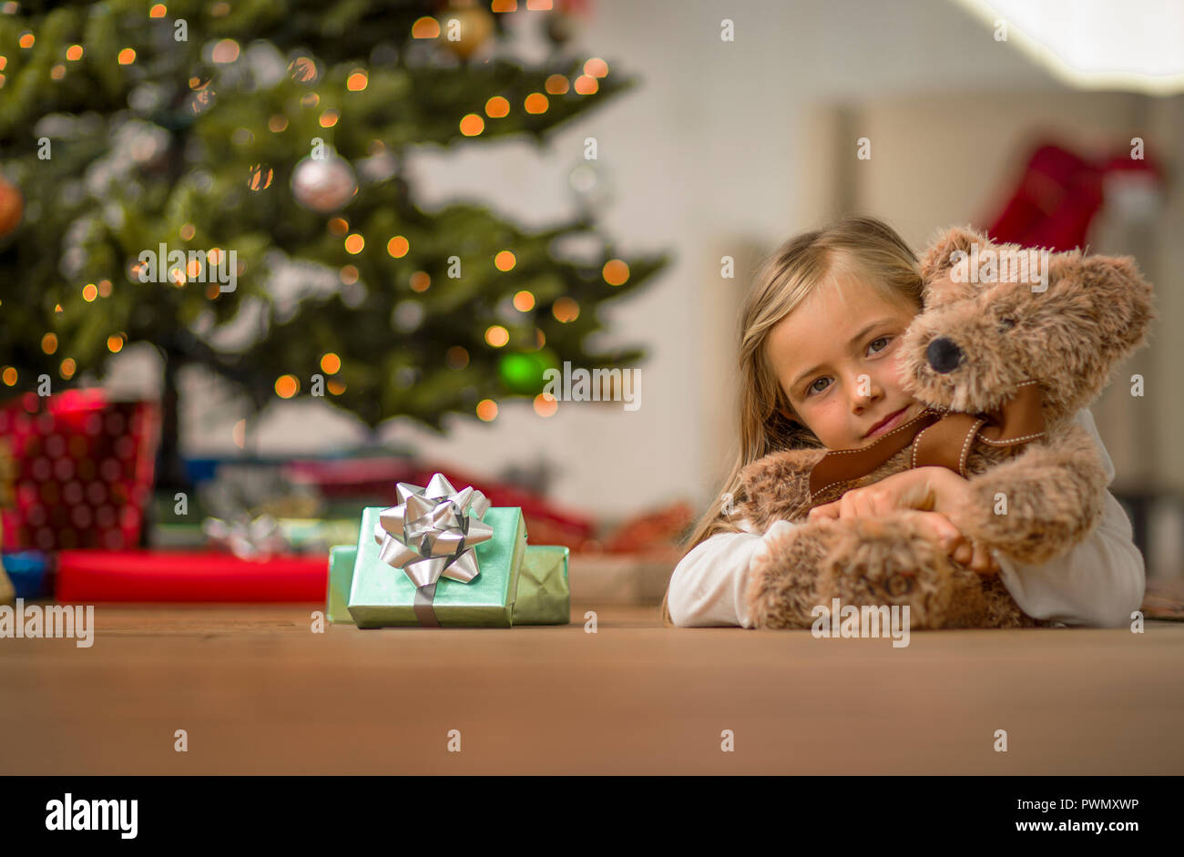 Portrait of a young girl hugging her teddy bear on Christmas morning ...