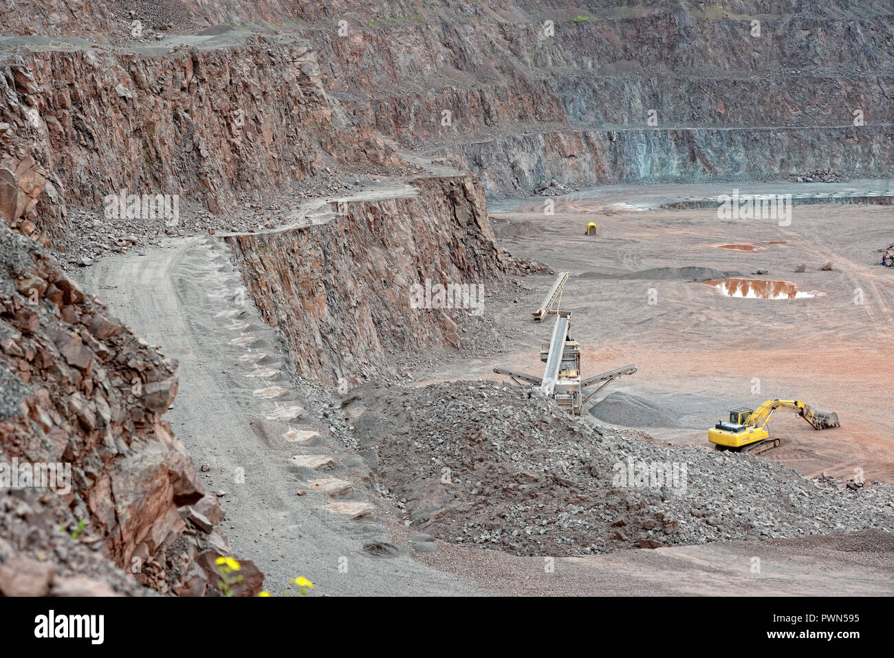 Stone crusher and excavator in a porphyry quarry. mining industry Stock Photo