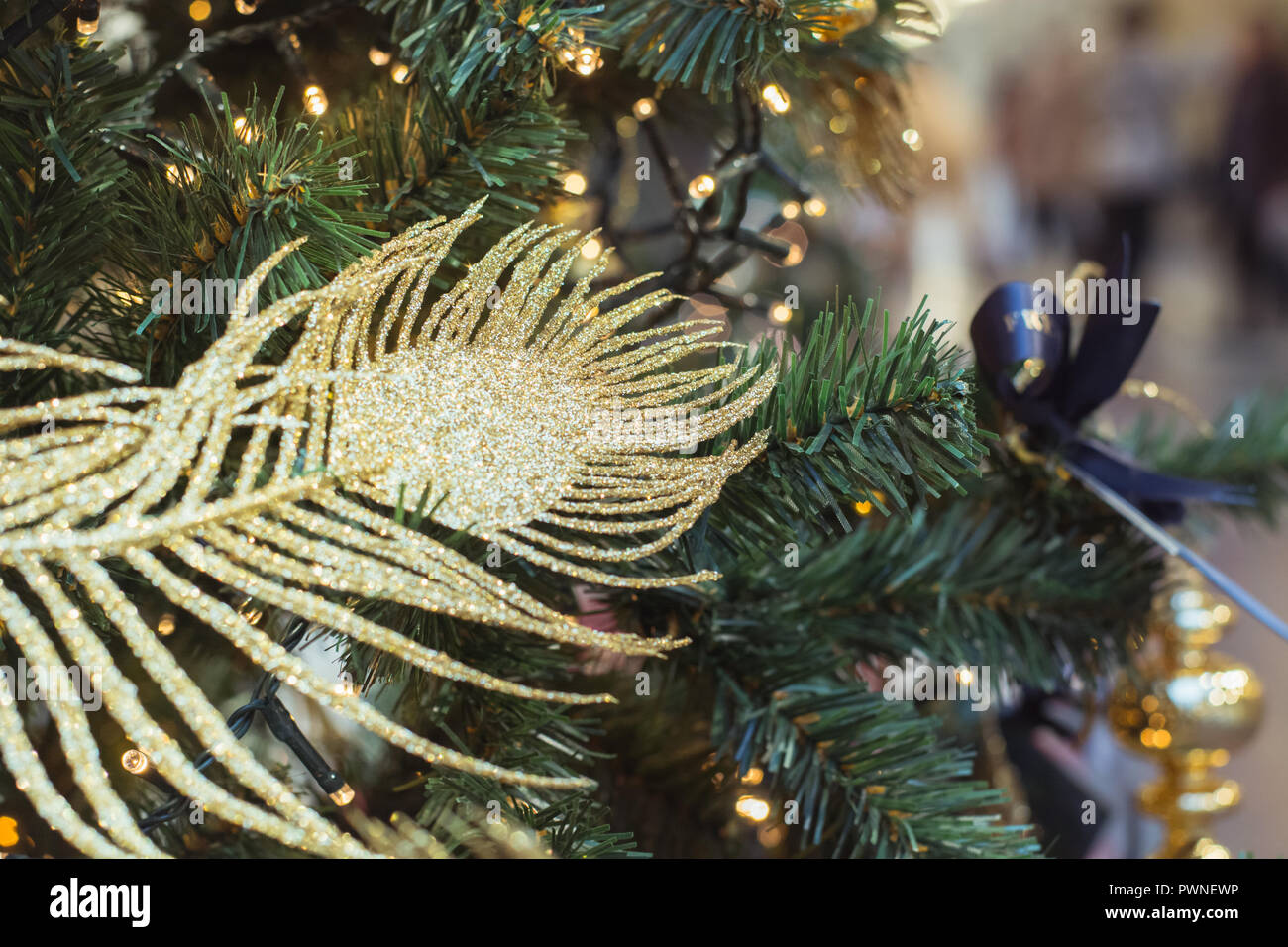 Christmas tree with golden luxury decor with copy space on blurred background in mall. Close up. Abstract Xmas pattern. Stock Photo