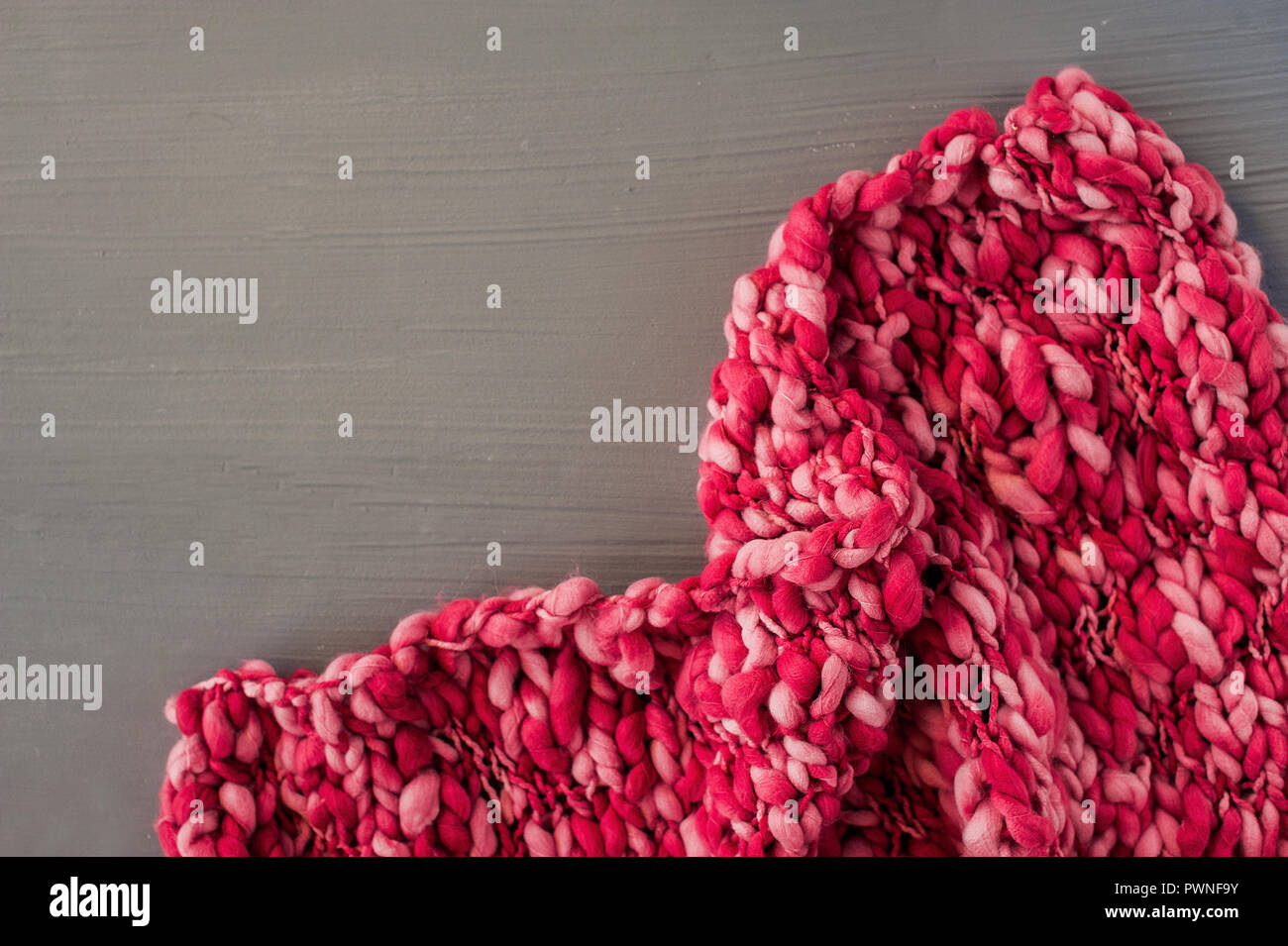 Pink knitting pattern on gray background. Space for text. Top view Stock Photo