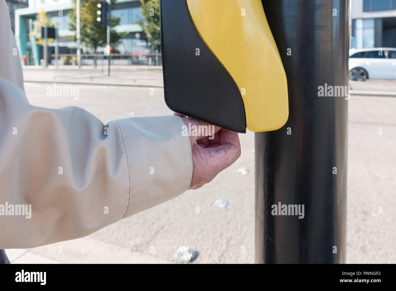 visually impaired blind elderly man using pedestrian road crossing rotating cone aid on underside of push button control box, Dundee, Scotland, UK Stock Photo