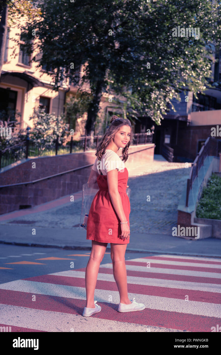 Appealing fashionable woman wearing dress and sneakers walking the street Stock Photo