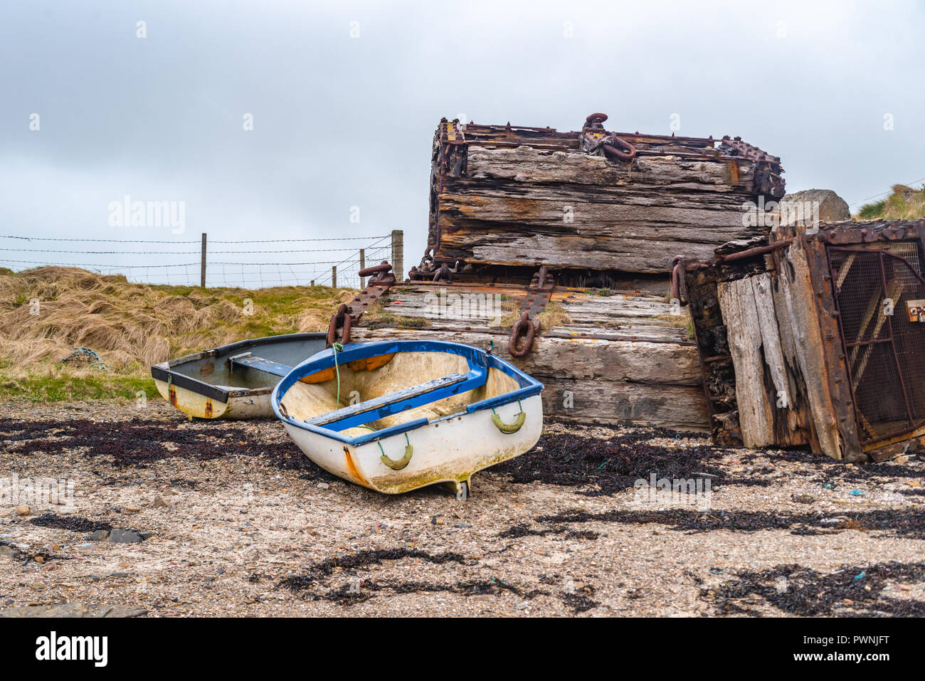 Old boats lying on the beach with flotsam. Scapa Flow, Orkney Islands, Scotland Stock Photo