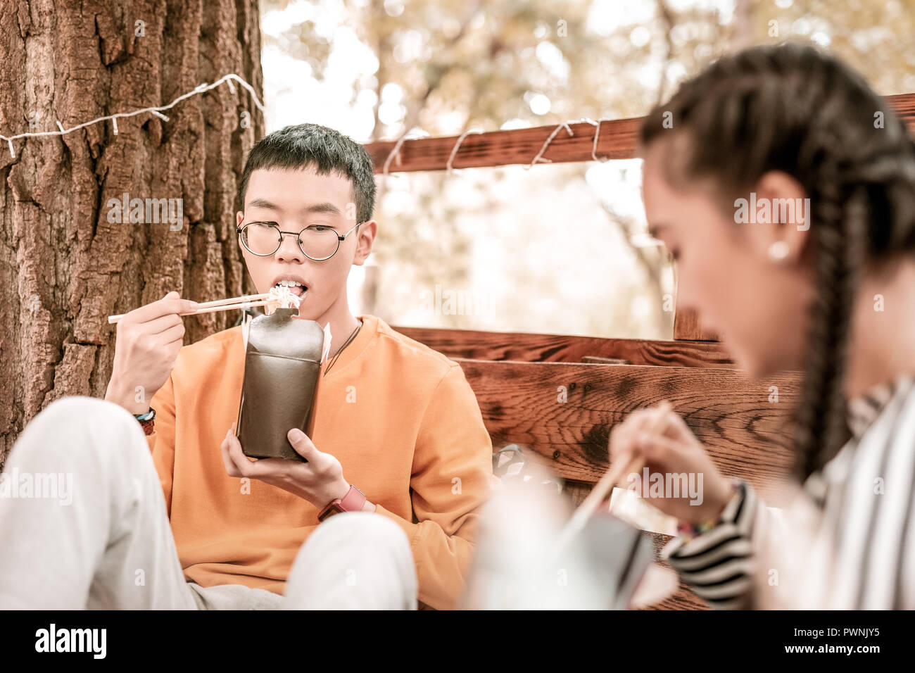 Concentrated Asian man eating his fast food Stock Photo - Alamy