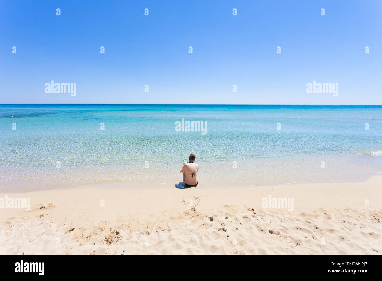 Lido Venere, Apulia, Italy - A young mother sitting on the beach looking towards the horizon Stock Photo