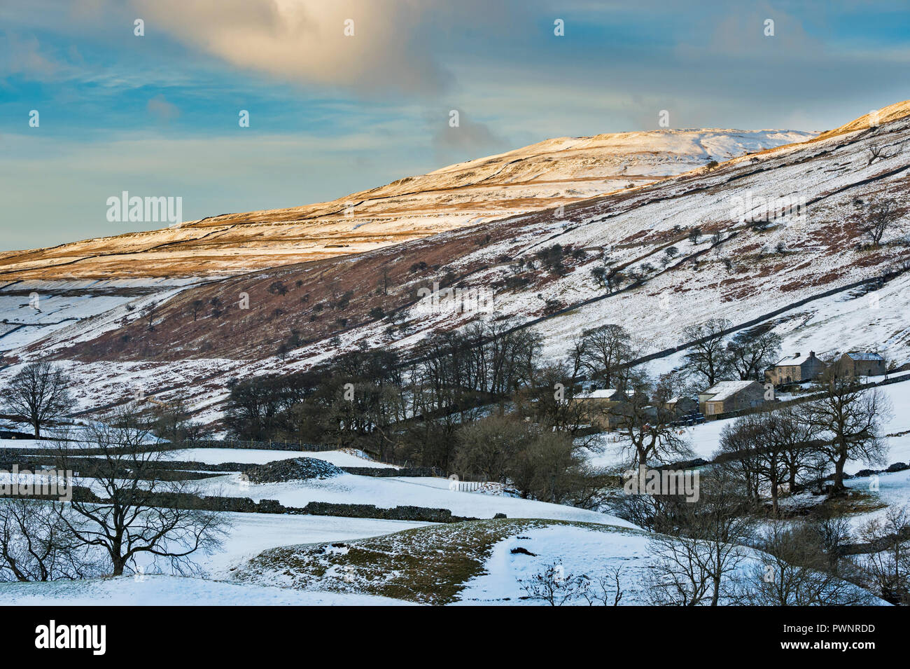 High view looking up remote scenic valley of Langstrothdale, Yockenthwaite Farm nestling under snow covered hills & blue sky - North Yorkshire, GB, UK Stock Photo