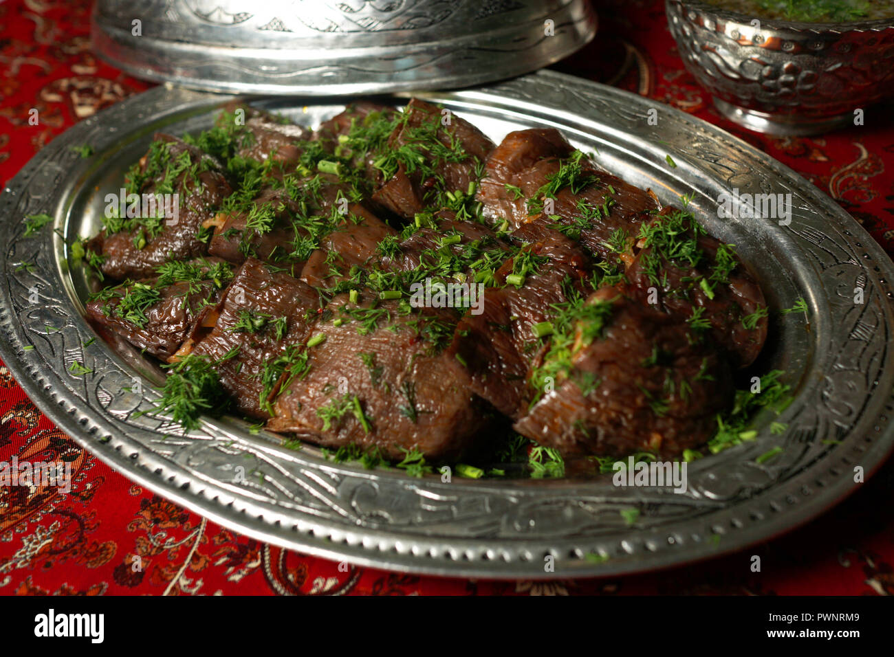 Stuffed eggplants from Turkish cuisine decorated with parsley presented in traditional copper plate and cap. Stock Photo