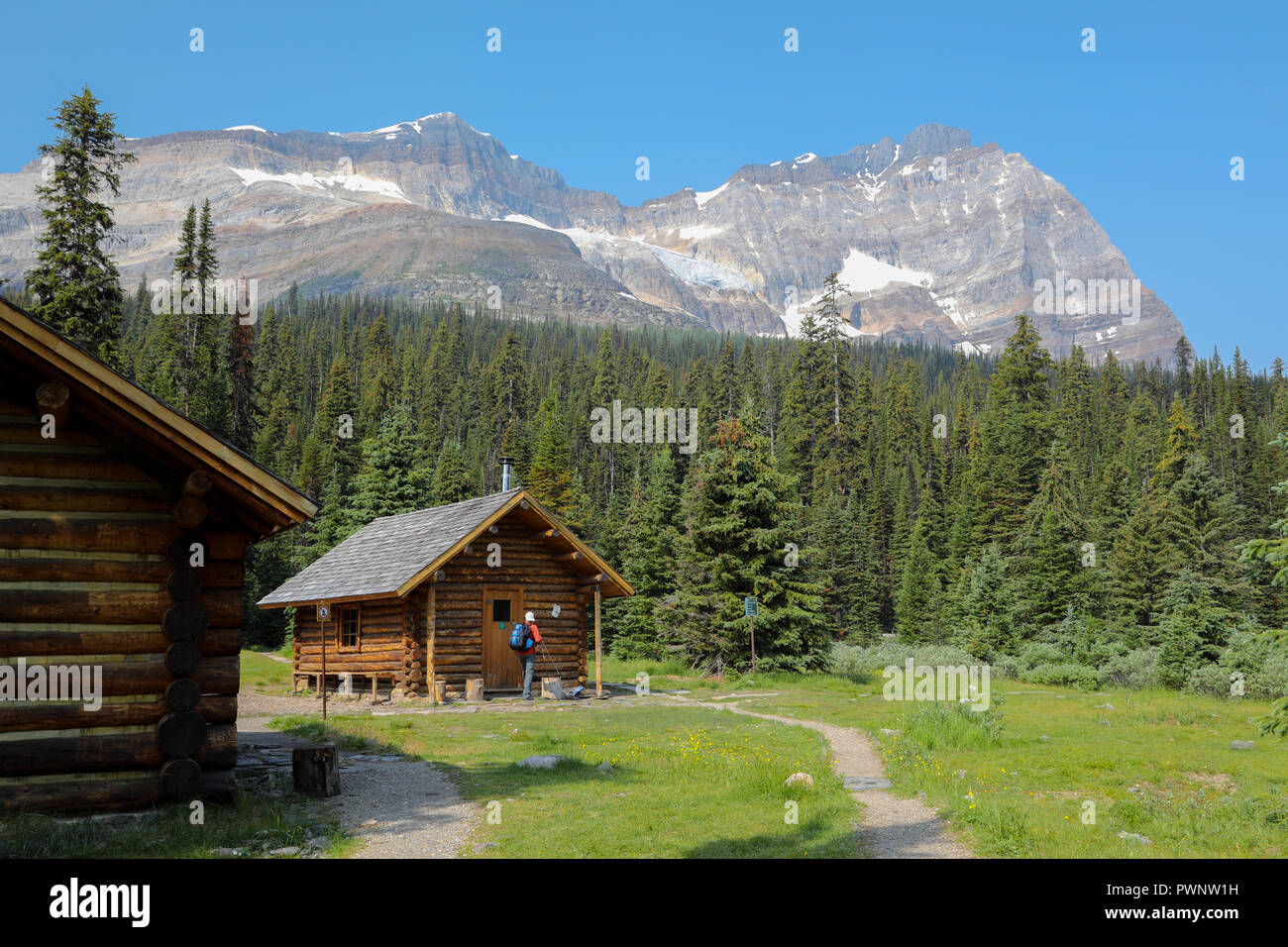 Alpine Cabin In The Mountains With A Hiker In Yoho National Park