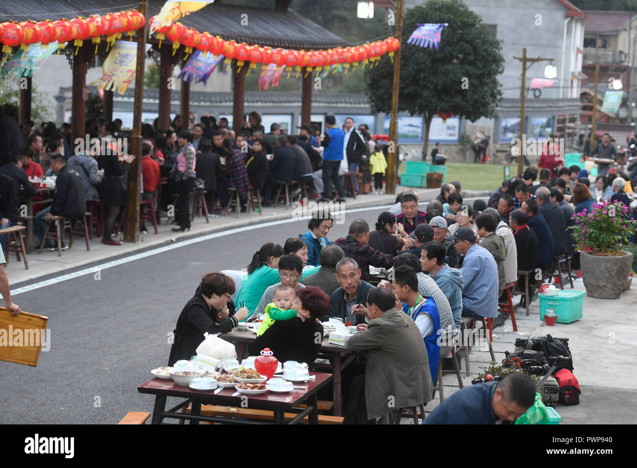 Tonglu, China's Zhejiang Province. 17th Oct, 2018. Local residents and tourists enjoy the long-table banquet held at Longfeng Ethnic Village in Eshan Township of the She ethnic group of Tonglu County, east China's Zhejiang Province, Oct. 17, 2018. A total of 100 tables of delicacies were presented at the long-table banquet along a street held at the village, attracting local residents as well as tourists to enjoy the food of the She ethnic group. Credit: Huang Zongzhi/Xinhua/Alamy Live News Stock Photo
