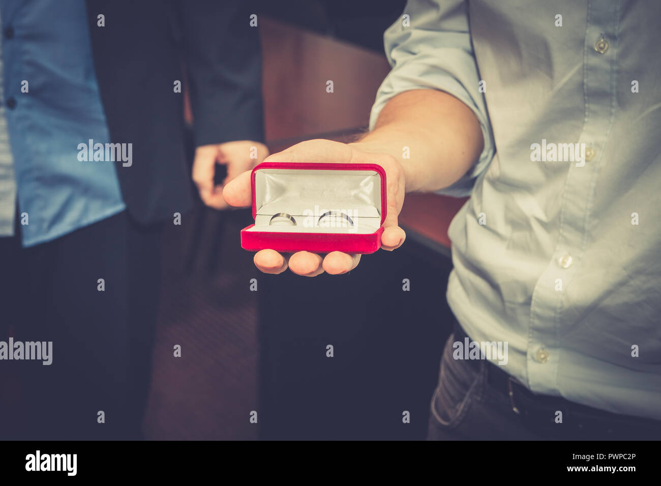 Best man holding red jewelry box with wedding rings. Close up. Stock Photo