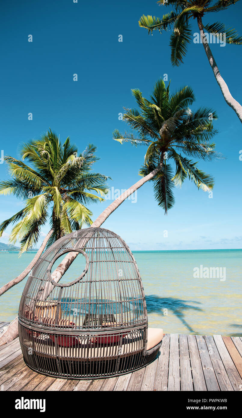 Rattan chair on wooden deck by the beach. Stock Photo