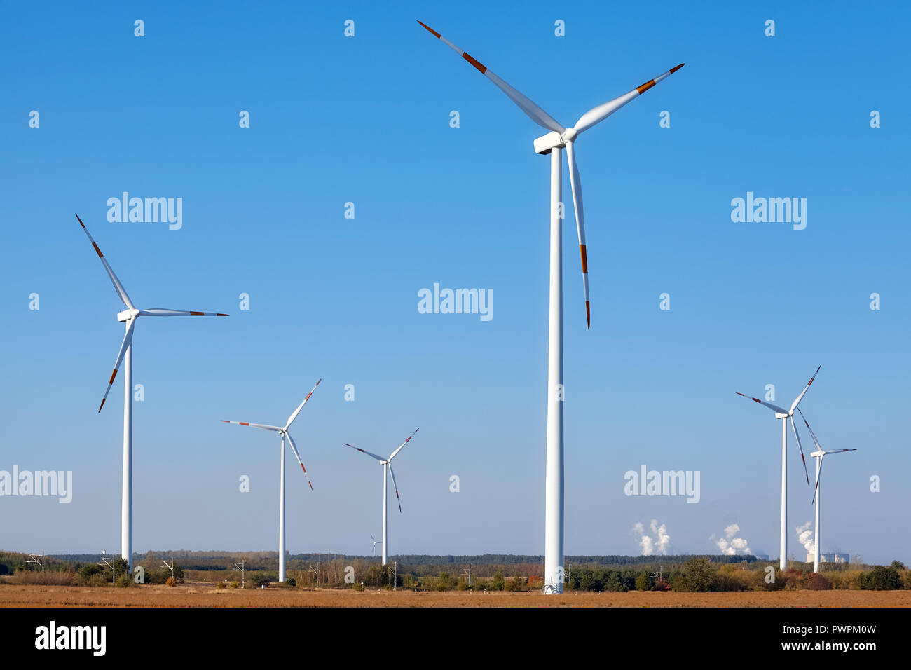 Windmills with smoking chimneys in background. Stock Photo