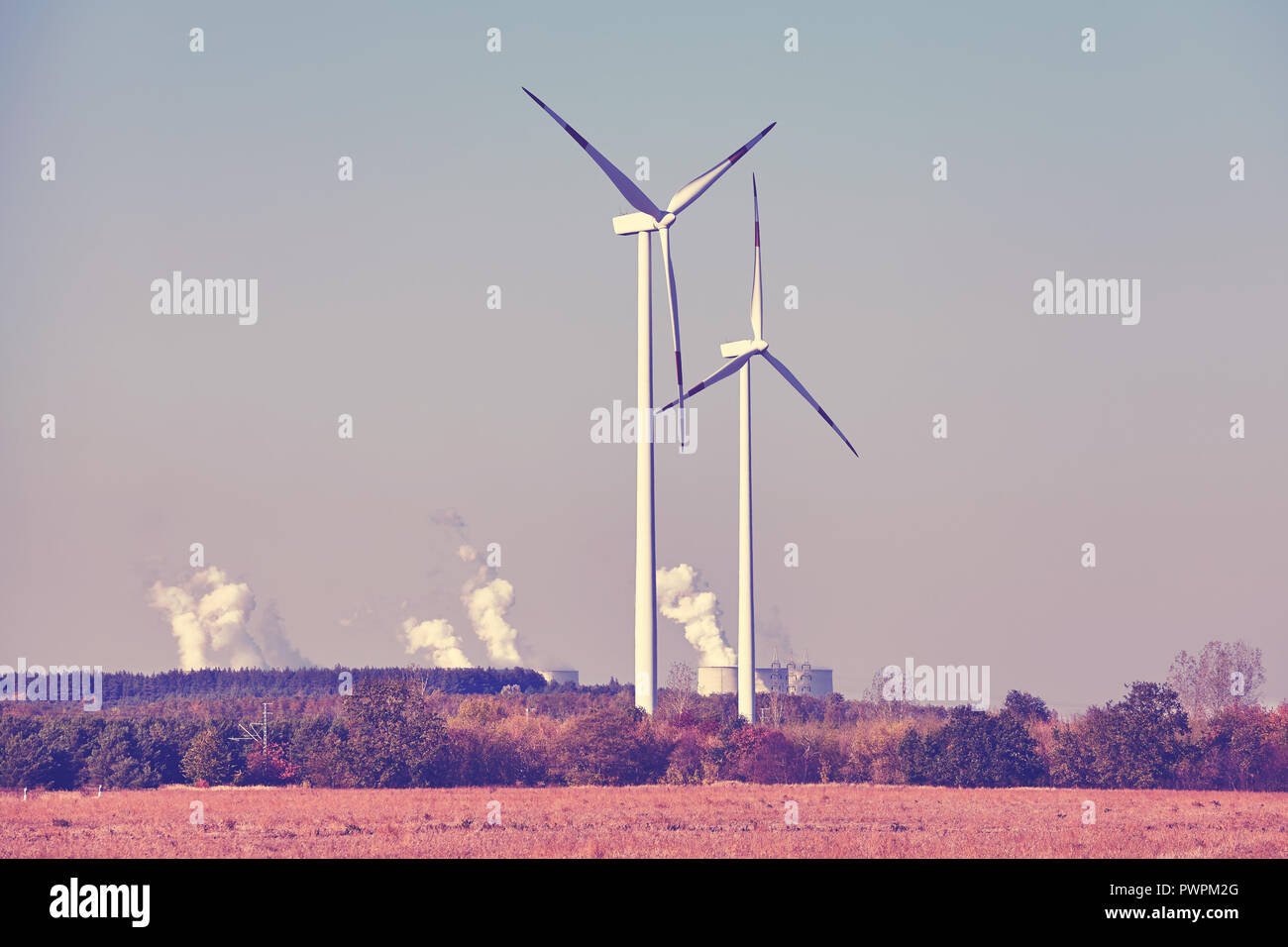 Windmills with smoking chimneys in background, color toned picture. Stock Photo