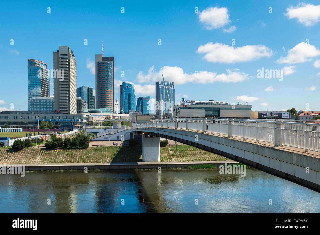 View of the White Bridge (Baltasis Tiltas) spanning the Neris River and the modern skyline of the Snipiskes business district in central Vilnius. Stock Photo