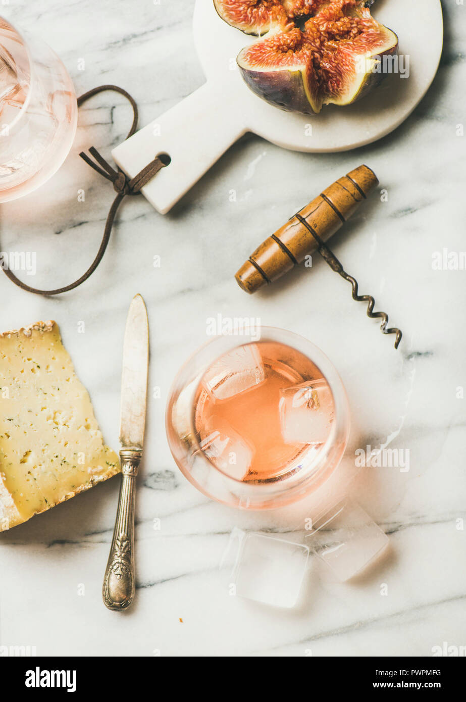 Flatlay of glass of rose wine with ice cubes, cheese and fresh figs on