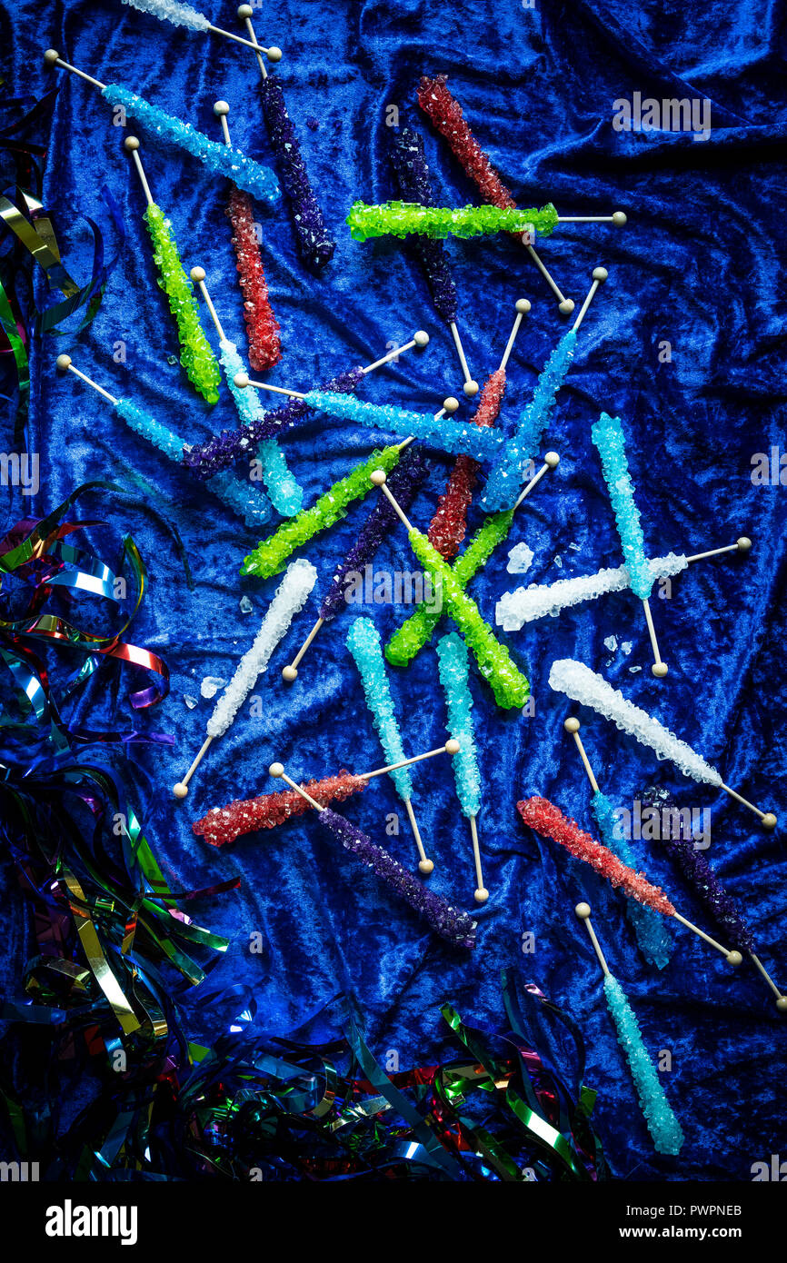 Very colorful assortment of rock candies on a blue velvet surface with sparkly streamers around. Stock Photo