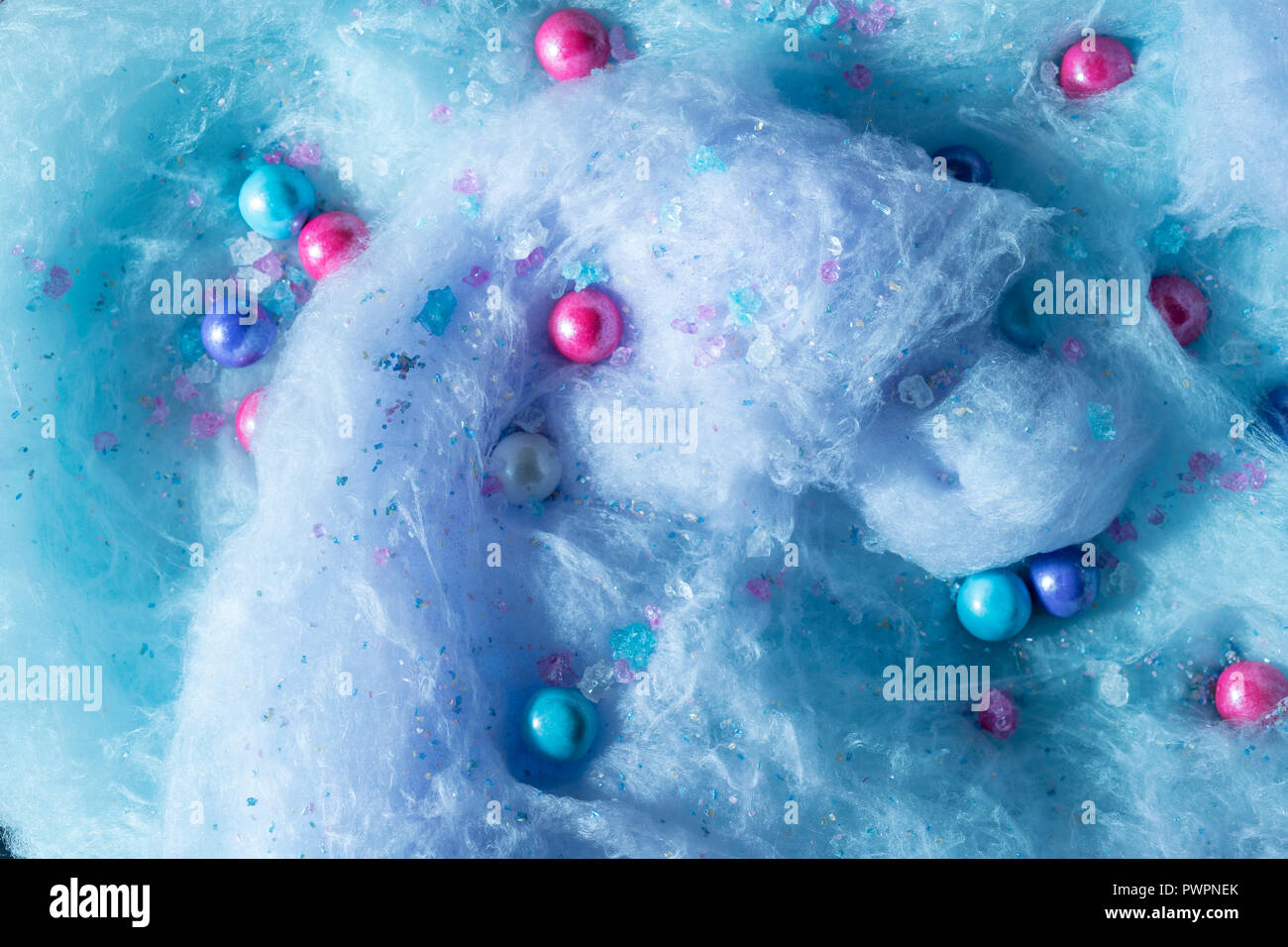 Giant swirl of blue and purple cotton candy with large gumballs and rock candies scattered throughout. Stock Photo