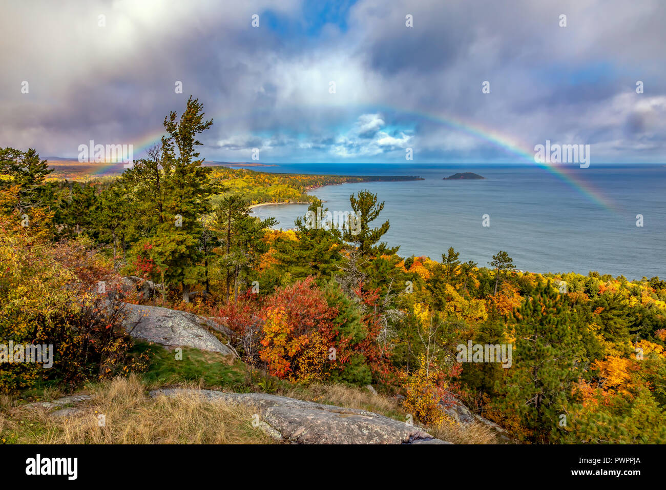 A rainbow stretches from land to Lake Superior at Sugarloaf Mountain near Marquette Michigan in Autumn Stock Photo