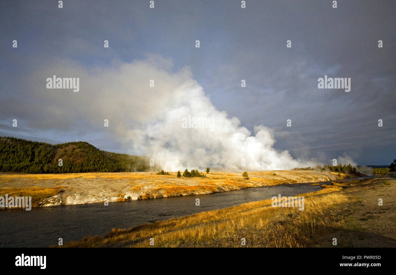 Hot steam rises above the Firehole river from one of the many geyser basins in Yellowstone National Park a few miles north of Old Faithful Lodge. Stock Photo