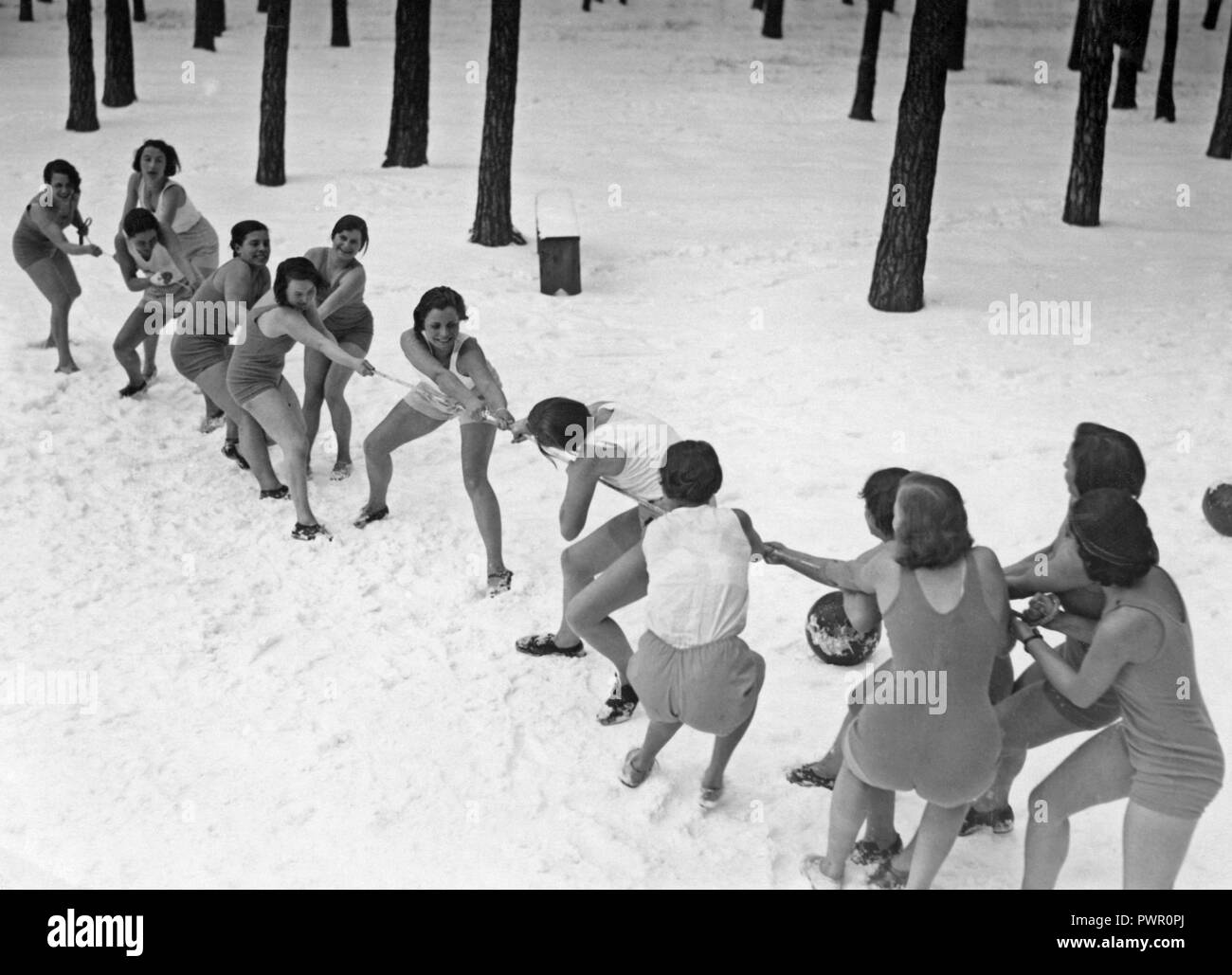 Tug of war wintertime.  Two teams of women in bathingsuits are having a tug of war in the snow. 1930s Stock Photo