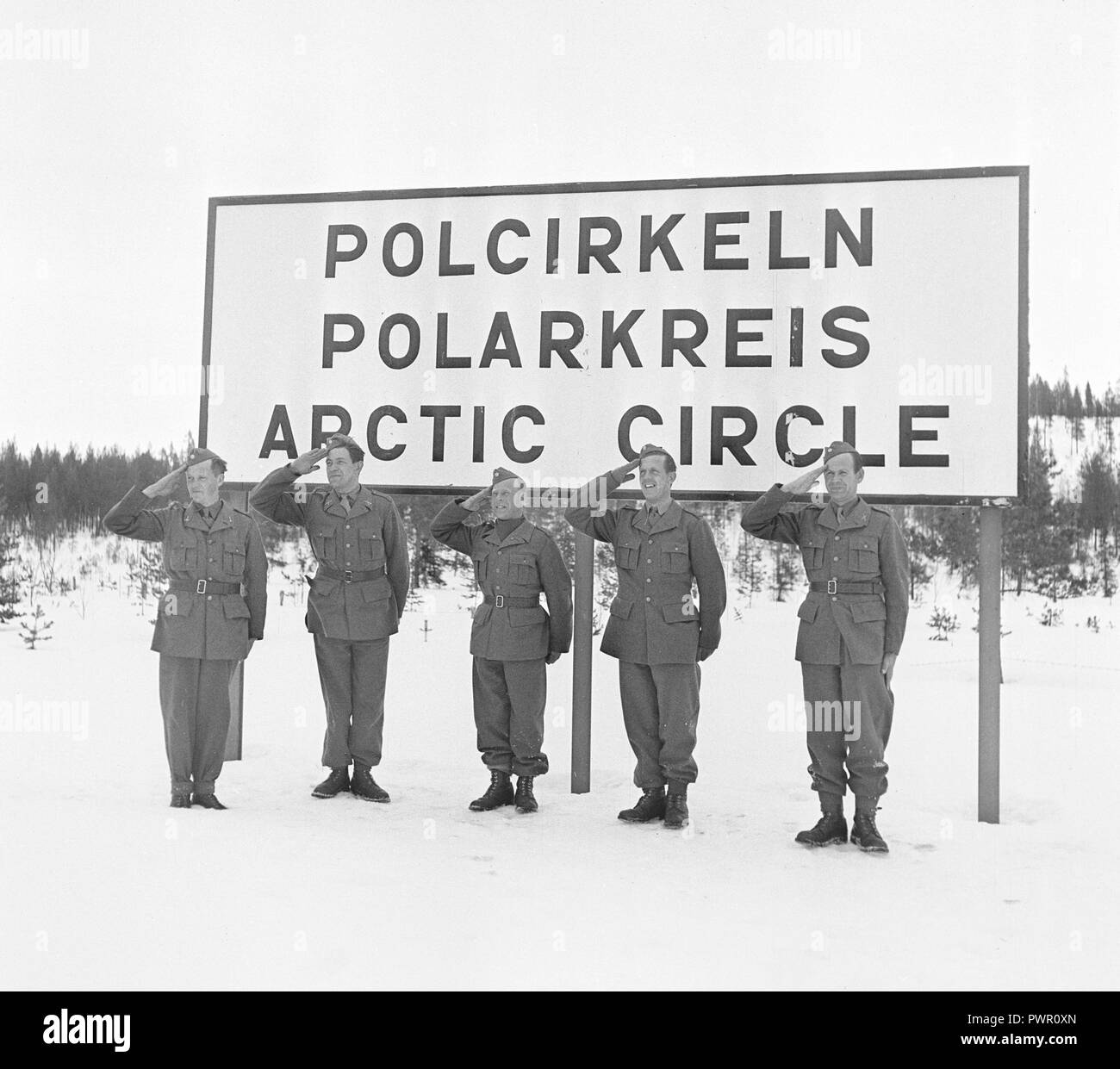 Arctic Circle in the 1940s. Five swedish soldiers are standing in attention saluting beneath a large sign at the Arctic Circle 1944. Photo Kristoffersson ref H75-6 Stock Photo