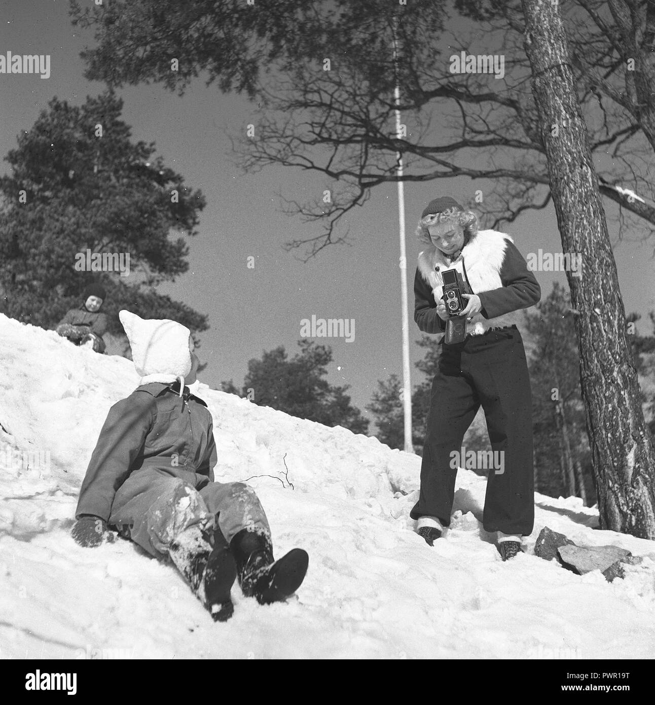 Winter in the 1940s. A young mother is photographing her daughter a winter day. The camera is a Rolleiflex.  Sweden 1944. Photo Kristoffersson Ref F104-2 Stock Photo