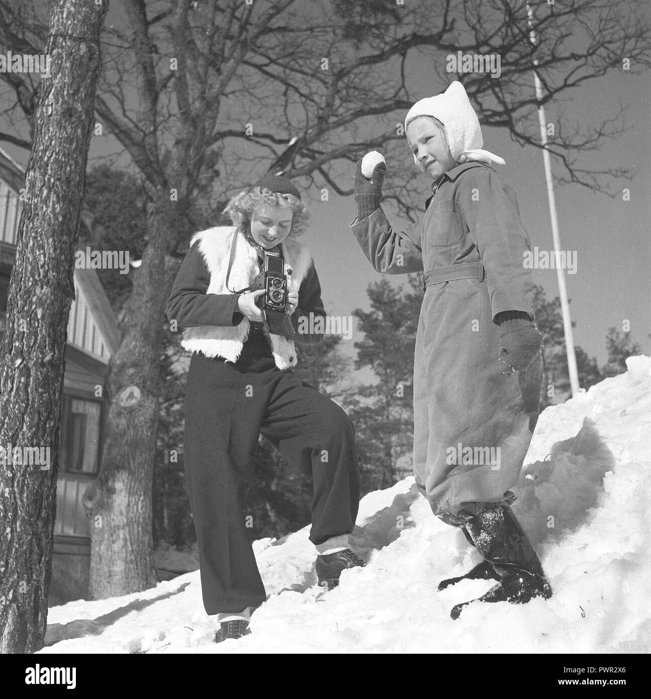 Winter in the 1940s. A young mother is photographing her daughter a winter day. The camera is a Rolleiflex by german company Rollei.  Sweden 1944. Photo Kristoffersson Ref N68-4 Stock Photo