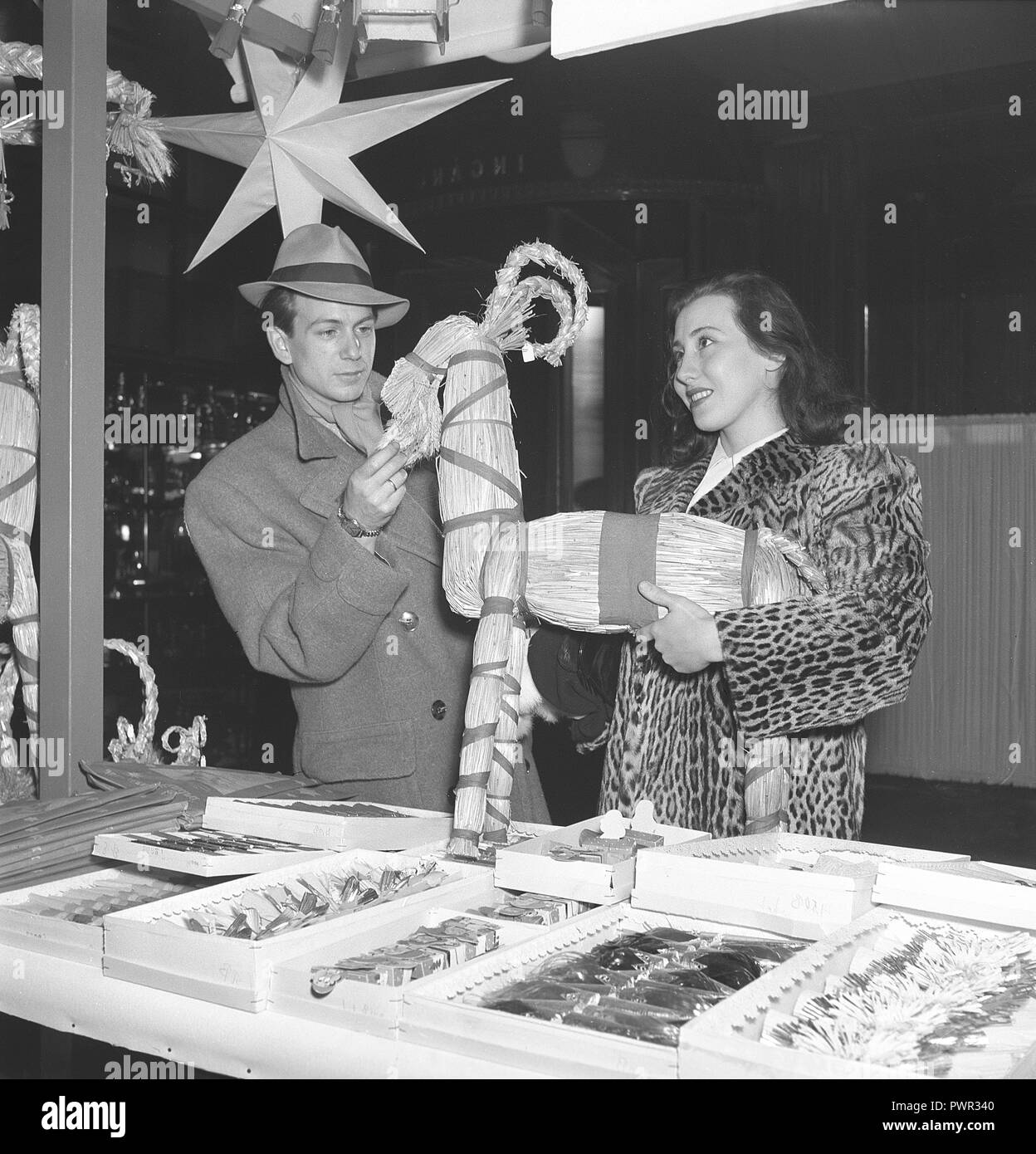 Christmas in the 1940s. A young couple is visiting a christmas market and have found a handmade christmas straw goat. Sweden 1945. Photo Kristofferson ref L45-5 Stock Photo