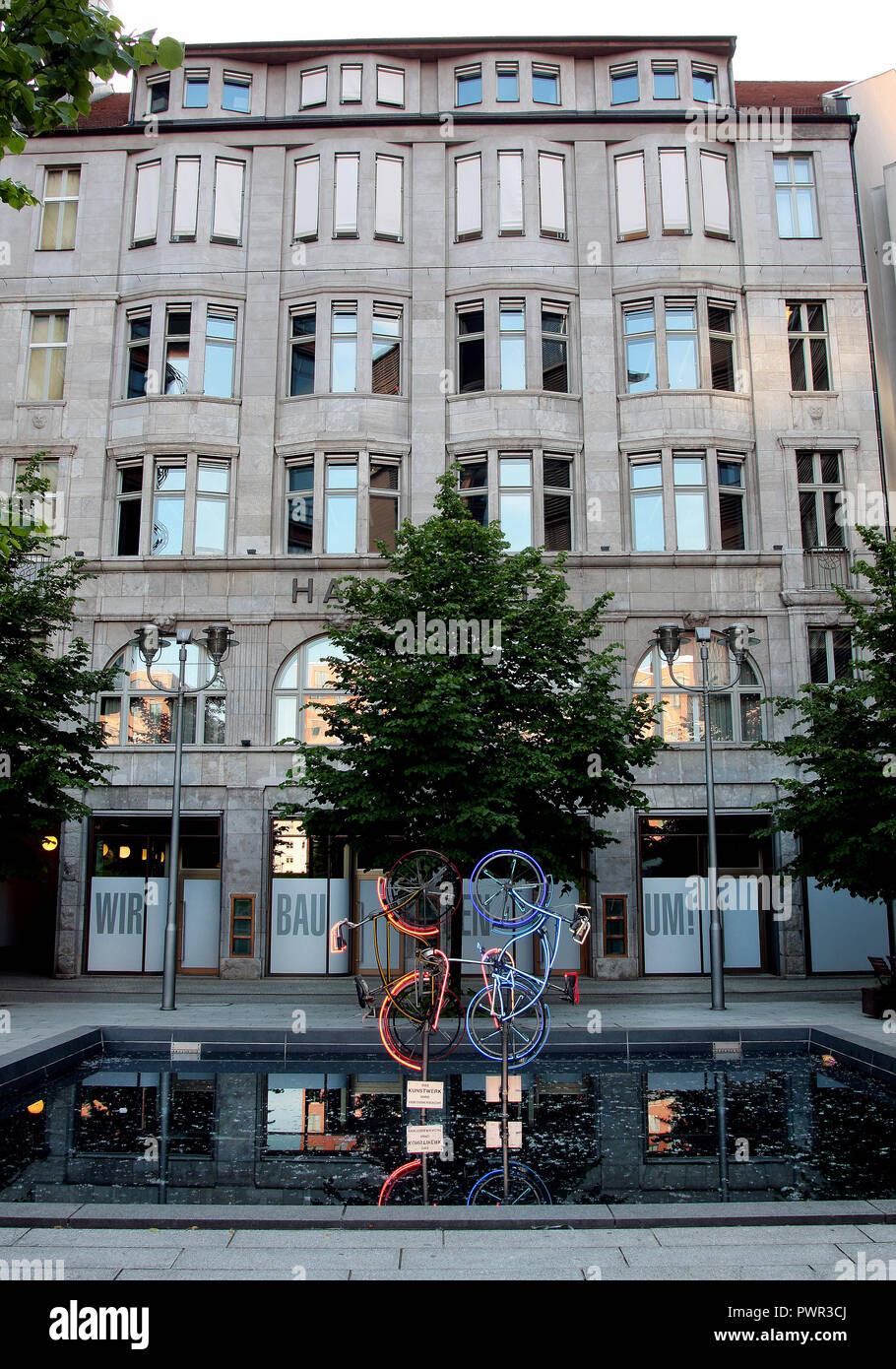 A neon bicycle art work, reflecting in a pond, in front of a classy building in Berlin. Stock Photo