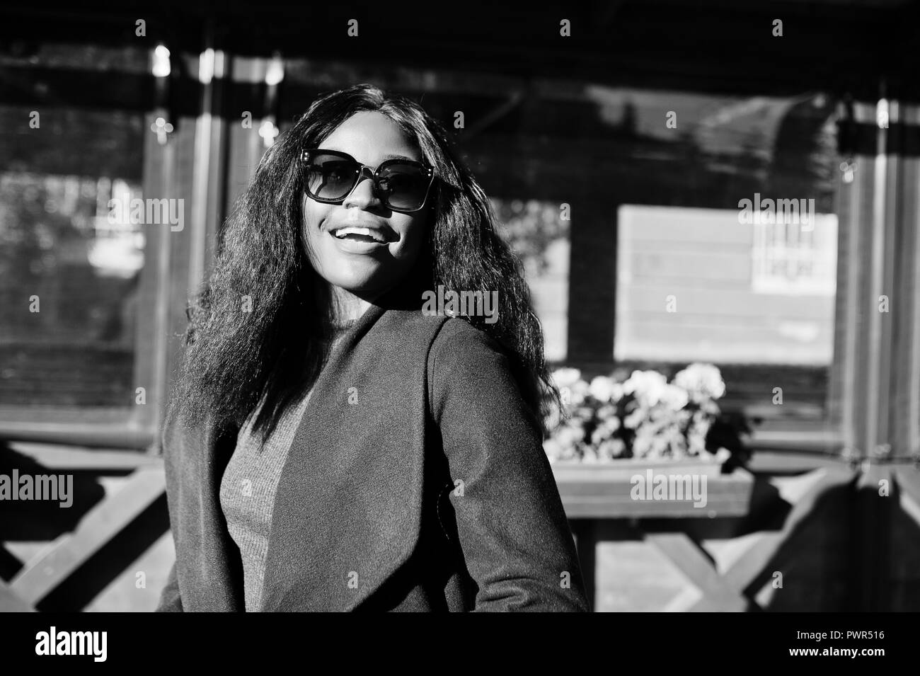 Stylish african american girl in blue coat and sunglasses posed at sunny autumn day. Africa model woman. Stock Photo