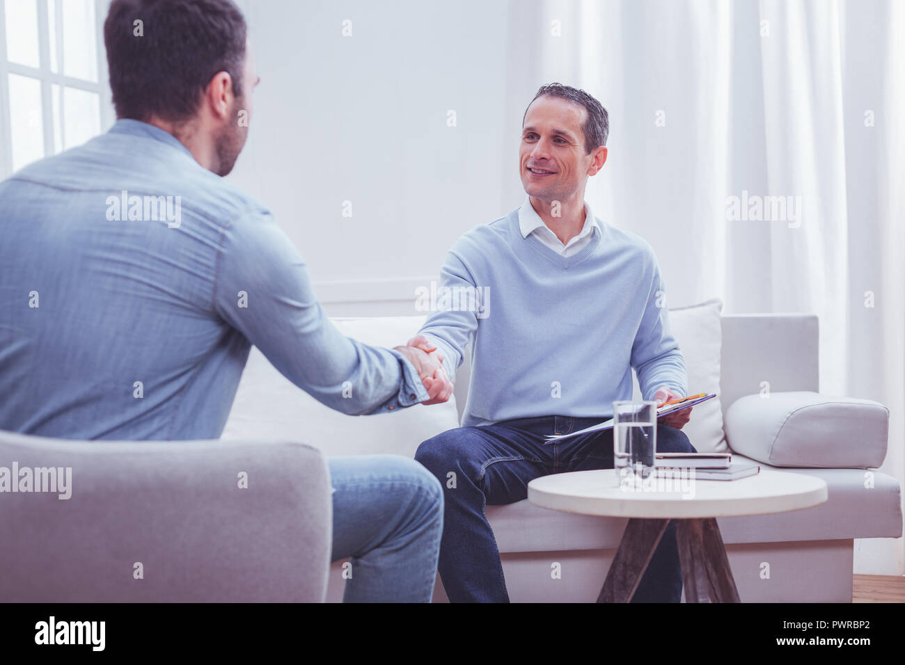 Cheerful psychiatrist saying goodbye to his client Stock Photo