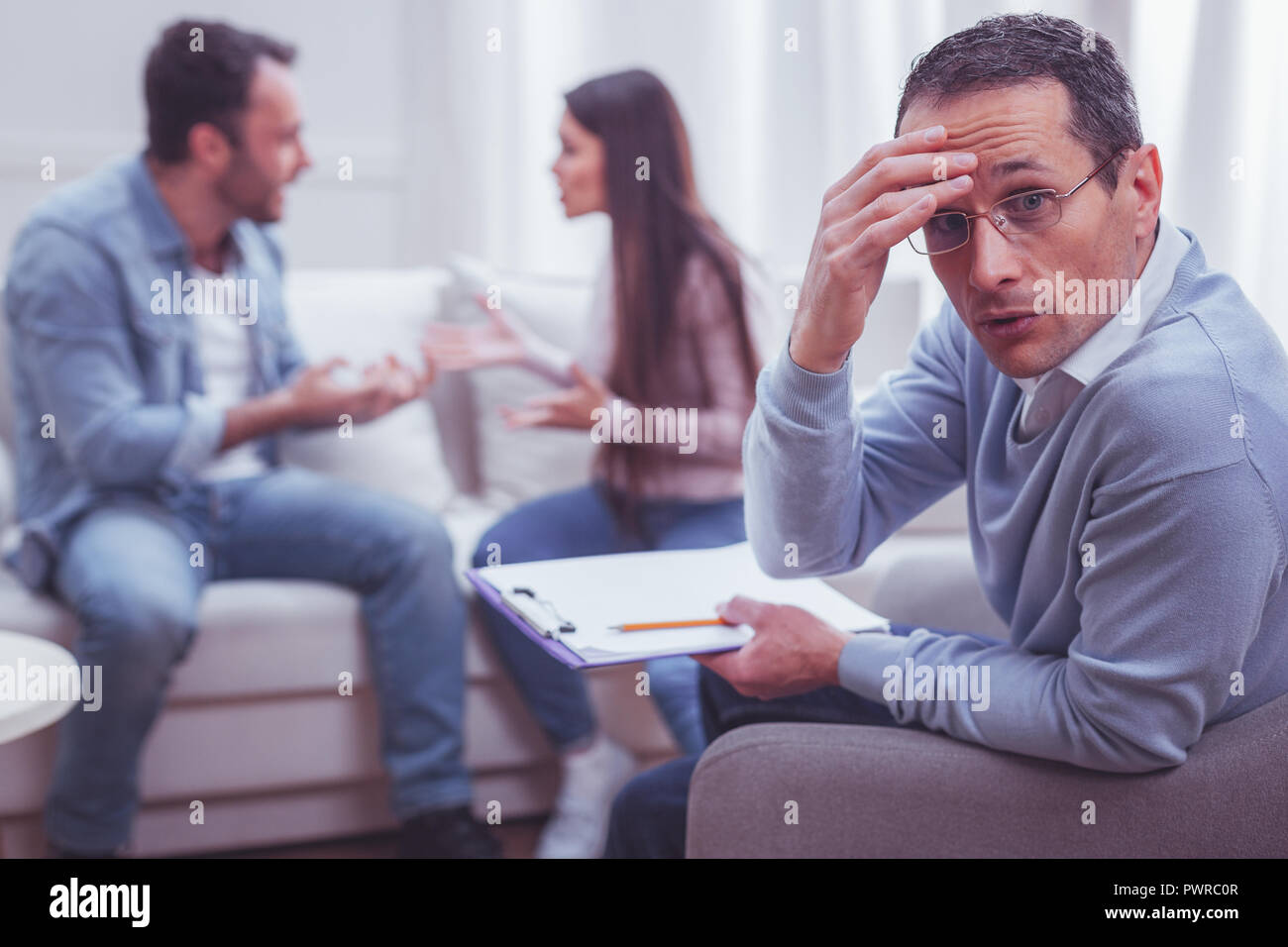 Nervous exhausted psychiatrist and his unbearable clients Stock Photo