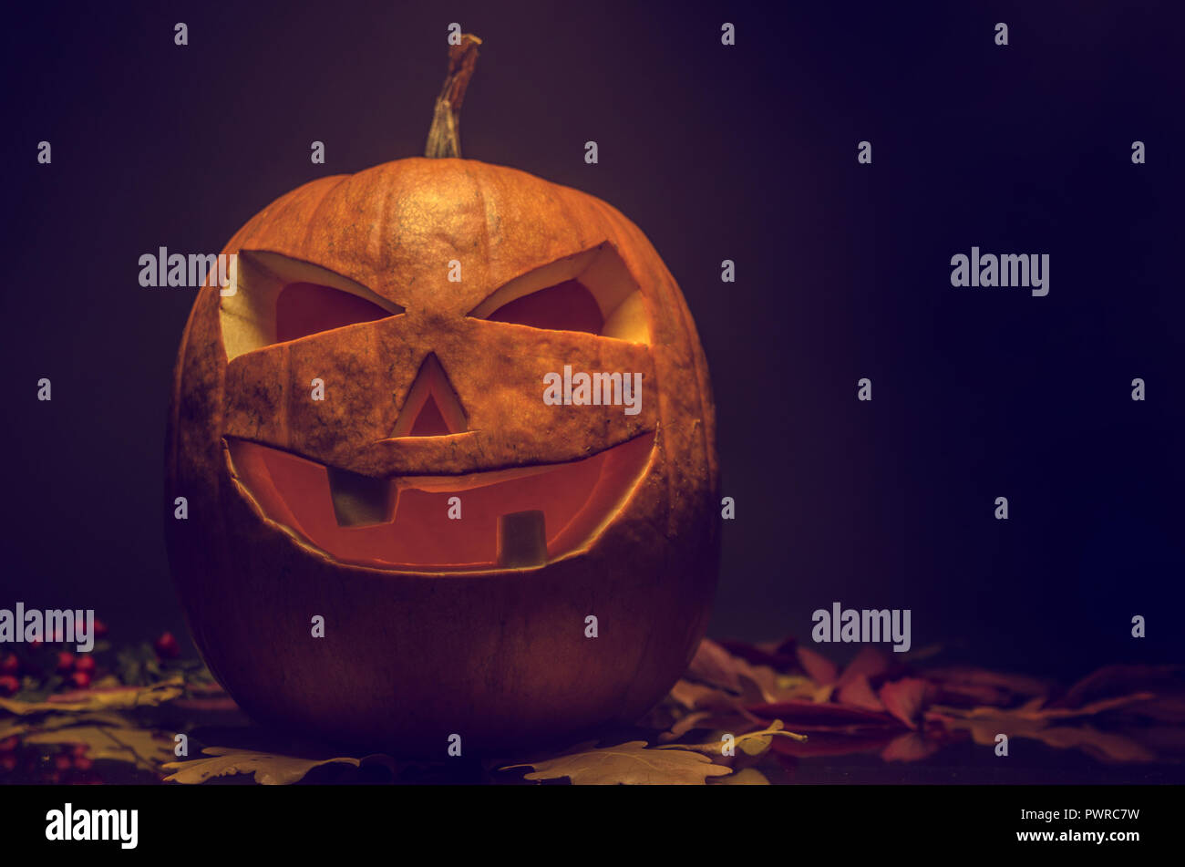 Top light halloween pumpkin lantern on dark fall background Stock Photo